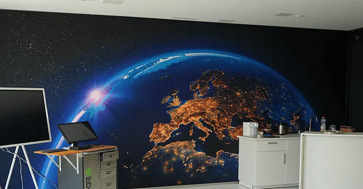 Showroom Bischofszell: heller Raum mit Wandbild der Erde bei Nacht, Bildschirm und Collab Trolley