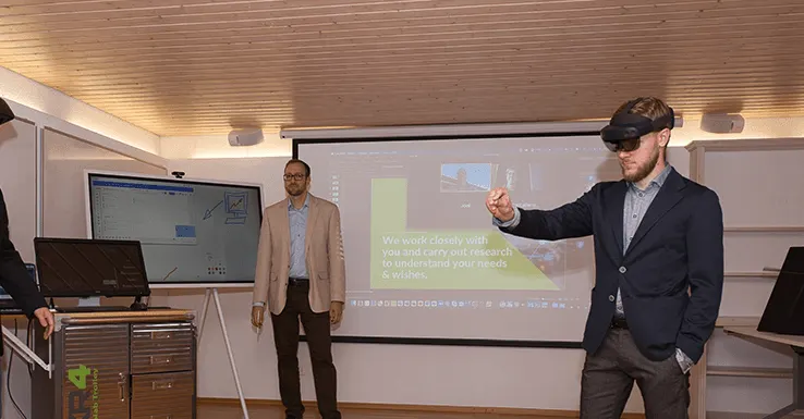 Vorführung im Showroom Ottikon: zwei Personen mit Datenbrillen, daneben der Collab Trolley und eine Wandprojektion